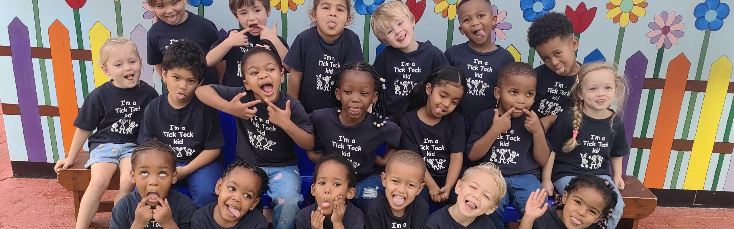 A group of children in colorful t-shirts smiling and posing together for a cheerful photo.