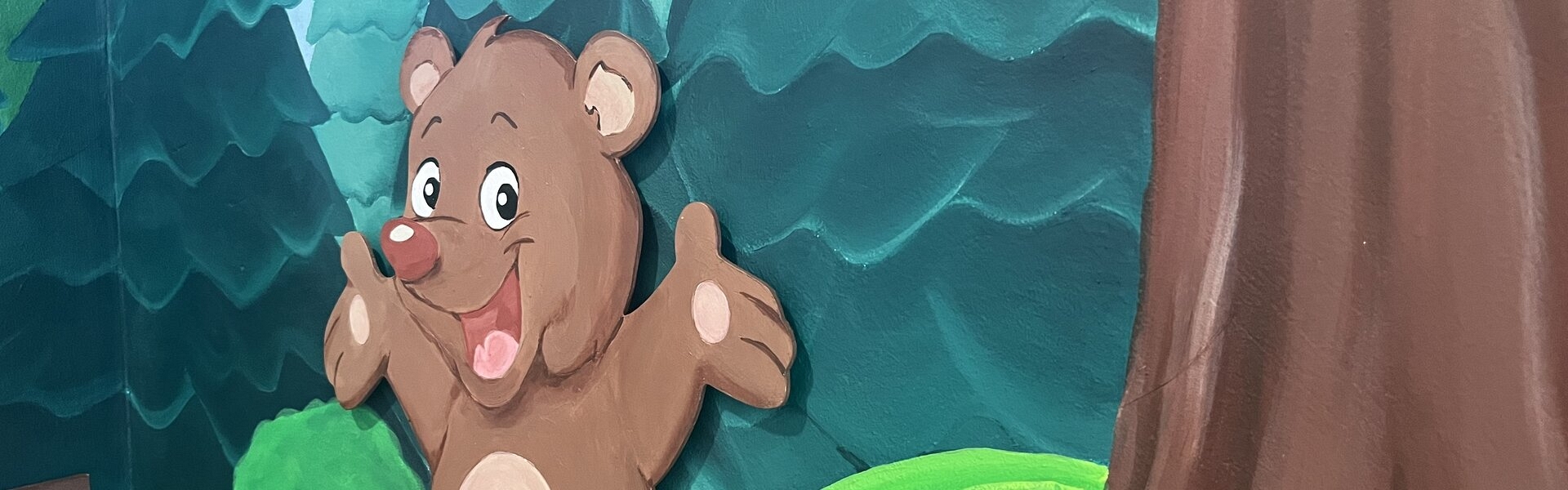 A playful cartoon bear resting on a stump, set against a backdrop of lush greenery in the woods.