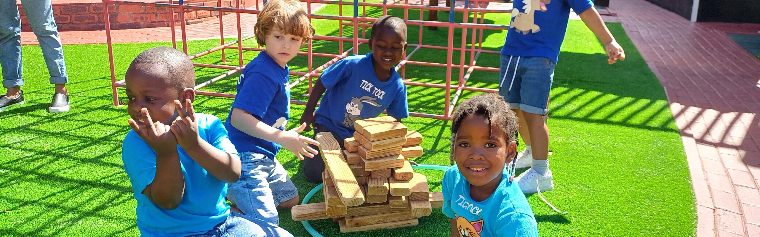 A joyful gathering of children seated on the ground, all smiling and sharing a moment of happiness together.