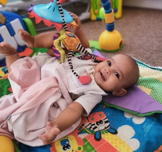 A baby happily lying on a colorful play mat surrounded by various toys, ready for fun and playtime.