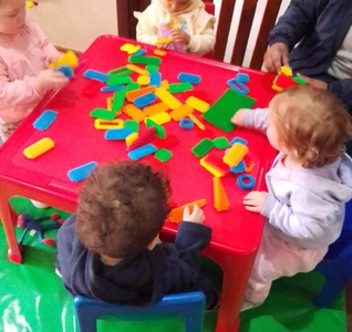 A fun scene of kids playing with blocks at a table, using their imagination to create different structures and designs.