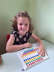 A young girl beams with joy as she plays with a bright and colorful puzzle, enjoying her fun activity.