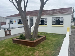 A view of the Cherie House entrance, showcasing its inviting doorway and charming design, framed by vibrant plants.