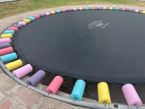 A vibrant trampoline adorned with an array of colorful balls resting on its surface, inviting playful activity.