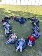 A group of kids sitting in a heart shape on a tire, smiling and enjoying their time together outdoors.