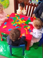 A fun scene of kids playing with blocks at a table, using their imagination to create different structures and designs.